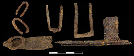 Historic sepia-toned photo of a street in Deadwood, South Dakota with store fronts on either side of a hard-packed dirt road. Horse drawn utility carts and people stand in and along the sides of the road.